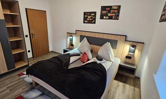 A modern bedroom with a double bed and bright walls. There is a wardrobe and decorative pictures on the wall.