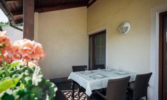 A quiet outdoor area with a table and chairs. Plants in the foreground create an inviting atmosphere.