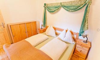 A cozy bedroom with a double bed and two bedside tables. The room is bright and cheerfully decorated.