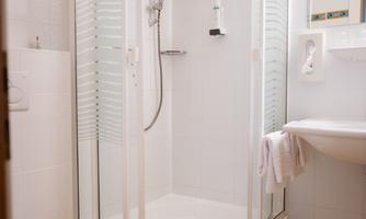 A modern bathroom with a round shower cabin and yellow tiles. The sink and toilet are functionally and simply designed.