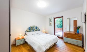 A cozy bedroom with a double bed and wooden floor.  
Large windows provide plenty of natural light and a view of the outdoors.