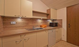 A modern kitchen with light cabinets and wooden countertops. It includes a sink, a dishwasher, and a microwave.