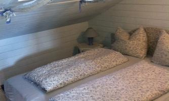 A cozy room with a double bed and colorful cushions. The window lets in plenty of light and creates a pleasant atmosphere.