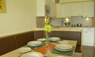 A bright dining room with a table set for several people. On the table, there is a vase with flowers.