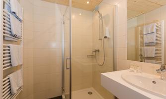 A modern bathroom with a shower niche and a sink. Towels are neatly hanging on the wall.