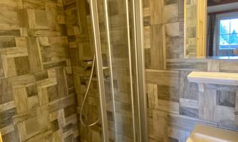 A modern bathroom with a glass shower stall and a sink. The walls are designed with a wood-look pattern.