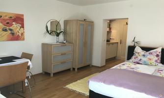 A cozy room with a double bed and a dining area. The furniture is modern and the space has plenty of daylight.