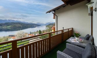 A beautiful balcony with seating and a view of the lake and the surrounding mountains. The atmosphere is calm and inviting.
