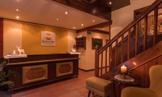 An inviting reception area with a wooden counter and warm lighting. The cozy atmosphere is emphasized by the wooden elements and candles.