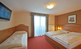 A cozy room with two beds and a TV on the wall. Plenty of daylight through the window and an inviting atmosphere.