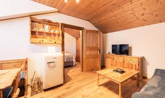 A cozy vacation apartment with wooden furniture and an inviting living area. The room layout offers a view of the kitchen and a television.