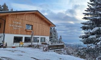 A cozy inn in a snow-covered landscape. The sky is overcast and the surroundings are quiet and wintry.