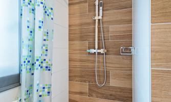 A modern shower with a wooden floor and a colorful shower curtain. The room is bright and invitingly designed.