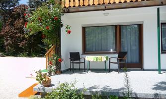 A cozy terrace with two chairs and a small table. Plants and flowers adorn the area, creating an inviting atmosphere.