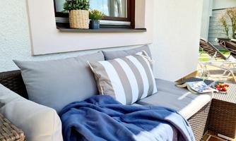 A cozy seating area with cushions and a blue blanket. On the table, there are some snacks and fresh fruit.