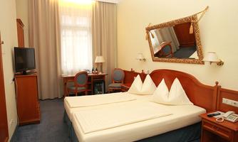 A cozy hotel room with a double bed and a desk. The relaxing atmosphere is enhanced by the bright decor and the large windows.