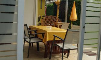 A cozy outdoor area with a table and chairs. A sunshade and a covered terrace provide protection from sun and rain.