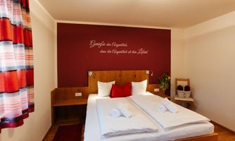 A cozy bedroom with a large bed and decorative pillows. The wall space is designed in warm colors and has an appealing window with curtains.