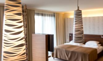 A modern hotel room with a double bed and stylish pendant lights. The large windows let in plenty of light and create an inviting atmosphere.