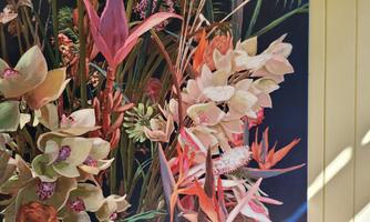 A colorful flower arrangement with various plants in soft colors. The composition appears lively and inviting.