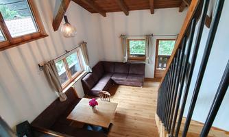 A cozy living space with wooden ceilings and large windows. The decor is modern and inviting, perfect for a relaxing stay.