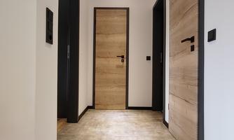 A modern hallway with several doors and a bright floor. The walls are painted in a neutral color and well-lit.