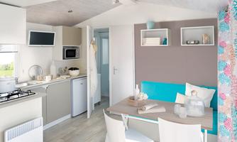 A modern kitchen with a dining area. The decor is bright and friendly, with blue accents and stylish details.