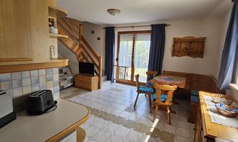A bright and welcoming kitchen with a dining area and a staircase. Large windows provide plenty of daylight.