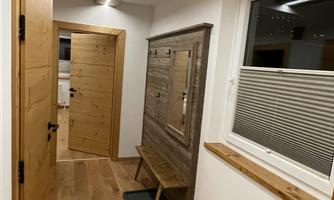 A bright hallway with wooden-paneled walls and a modern shoe rack. The atmosphere is cozy and inviting.