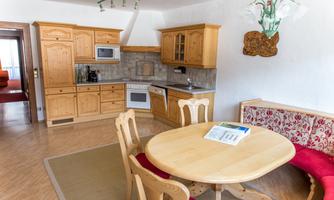 A cozy kitchen with bright wooden furniture and a round dining table. It is well-equipped with modern appliances and offers an inviting atmosphere.