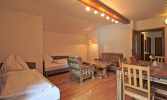 A cozy living space with a table, chairs, and a couch. There are two sleeping accommodations and plenty of daylight.