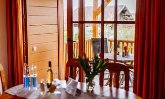 An inviting view from a wooden room onto a terrace with chairs. The table is decorated with drinks and a floral arrangement.