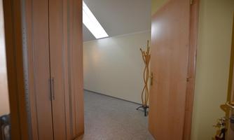 A bright hallway with a large wooden wardrobe. There is a simple coat rack against the wall.
