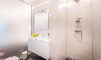 A modern bathroom with a shower and an elegant sink. Bright walls and a minimalist decor create a clean atmosphere.