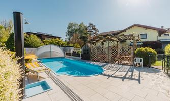 An inviting outdoor area with a small swimming pool and lounge chairs. In the background, there are plants and a decorative privacy screen.