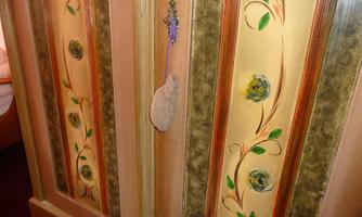 A decorative cabinet with artistic floral patterns in soft colors. A small decorative strip hangs on the door.