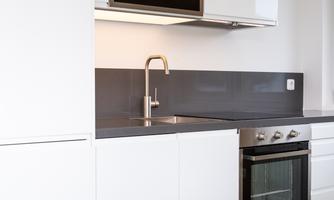 A modern kitchen with white cabinets and sleek appliances. The countertop is dark and provides a stylish contrasting color.