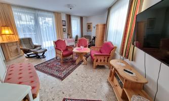 A cozy living room with red armchairs and stylish furniture. Large windows ensure plenty of daylight.