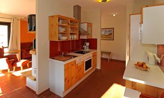 A modern kitchen with wooden cabinets and red tiles.  
Plenty of natural light streams through the window.