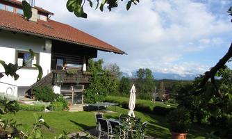 A beautiful house with a large garden. In the background, there are trees and a clear sky.