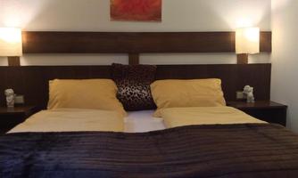 A cozy bedroom with a double bed and yellow pillows. Next to the bed are two nightstands with lamps.