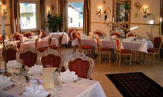 An elegantly furnished dining room with beautifully set tables and stylish chairs. The atmosphere is inviting and perfect for festive occasions.