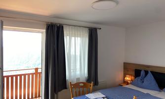A cozy room with a double bed and a balcony. Large windows provide plenty of daylight and a pleasant atmosphere.