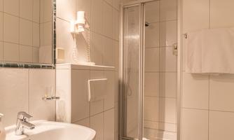 A modern bathroom with bright tiles. It features a sink, a shower, and a toilet.