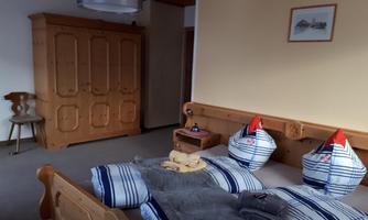 A cozy bedroom with a wooden bed and matching bedding. A picture hangs on the wall, and a wardrobe is in the corner.