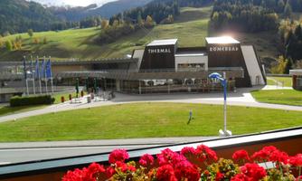 A modern thermal bath with a well-maintained outdoor area. In the background, green hills and trees can be seen.