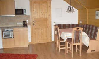A cozy kitchen with wooden details and a dining area. The space has a warm, inviting character.