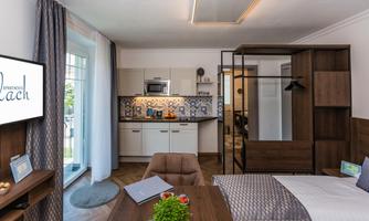 A modern apartment with an open kitchen and a cozy living area. The decor is stylish and inviting, with a television and a large window.