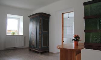 A bright room with a decorative cabinet and a small wooden table. Natural light comes in through a window.