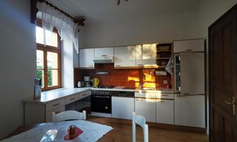 A modern kitchen with bright furniture and plenty of daylight. The space is equipped with appliances and has a cozy dining area.